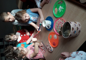 dzieci malują pierniki lukrem i ozdabiają je posypką